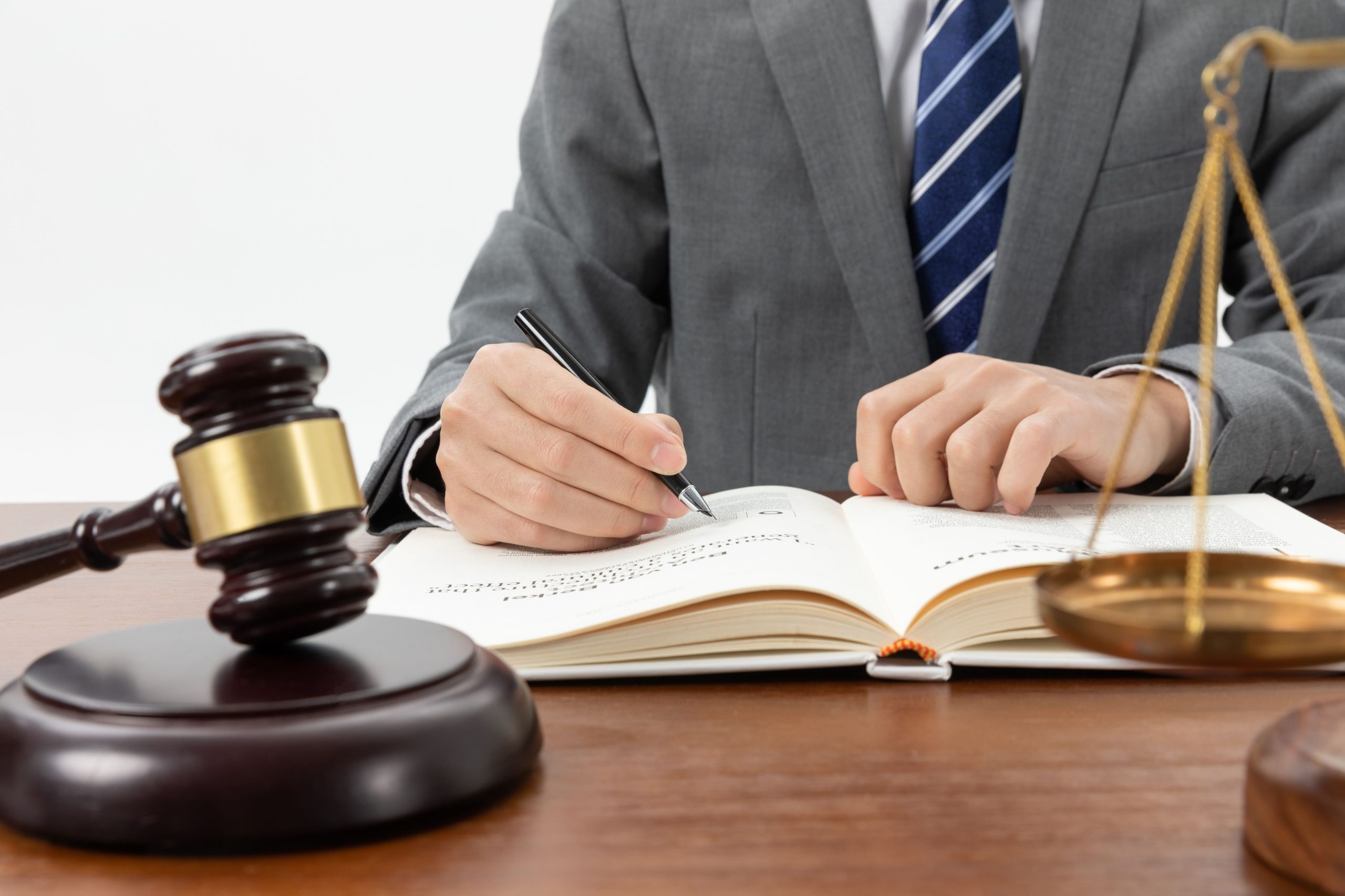 closeup-shot-person-writing-book-with-gavel-table-2-scaled.jpg